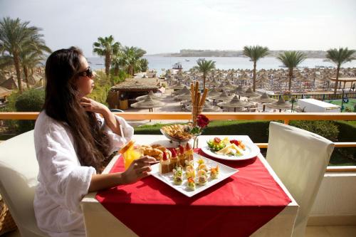 a woman sitting at a table with a plate of food at Gafy Resort Aqua Park in Sharm El Sheikh