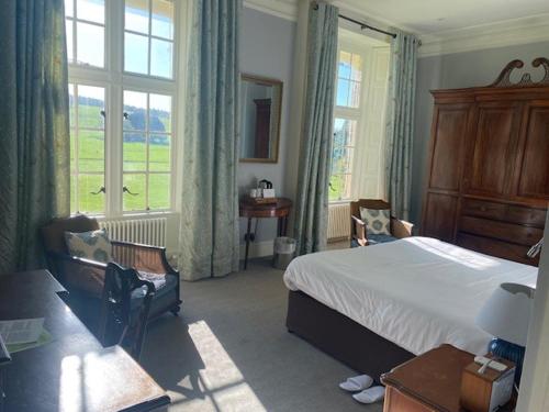 a bedroom with a bed and a desk and windows at West Dean College in West Dean