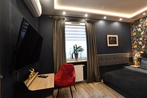 a bedroom with a red chair and a table and a window at Green Penthouse in Grudziądz
