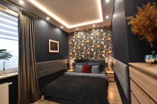 ein Schlafzimmer mit einem Bett und einer mit Blumen bedeckten Wand in der Unterkunft Green Penthouse in Graudenz