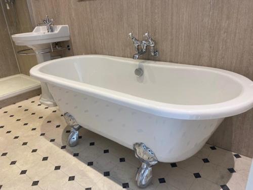 a white bath tub in a bathroom with a sink at West Dean College in West Dean