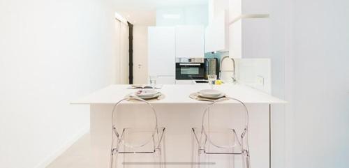 een keuken met een wit aanrecht met 2 krukken bij Luxury Madrid Centro in Madrid