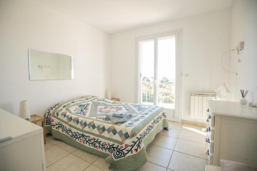 een witte slaapkamer met een bed en een raam bij Villa Cécile in Draguignan