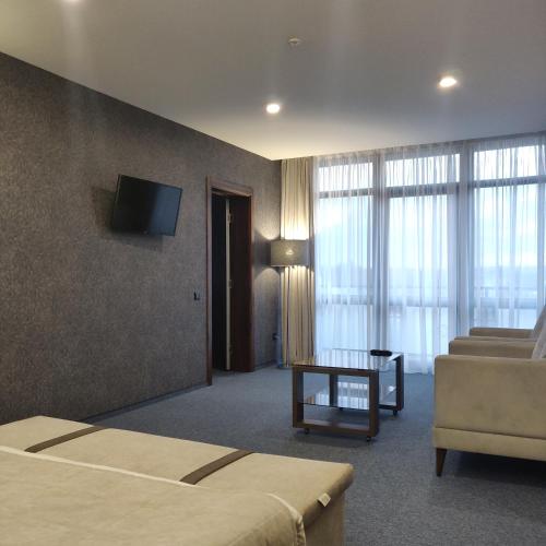 a hotel room with a bed and a couch and a television at Hotel Zefir in Drohobytsch