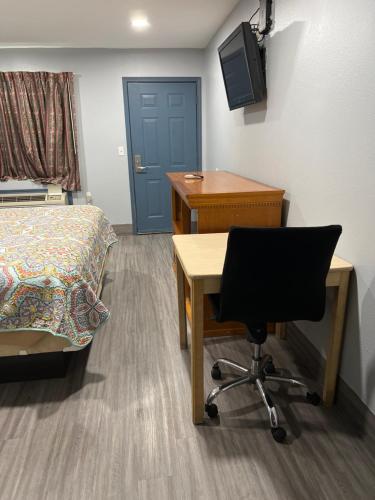 een kamer met een bureau, een bed, een bureau en een stoel bij Budget Inn in Hallettsville