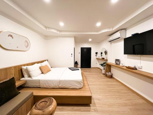 ein Schlafzimmer mit einem Bett, einem TV und einem Sofa in der Unterkunft KohLan Hansa in Ko Larn
