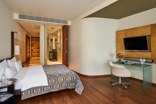 a bedroom with a bed and a desk and a television at DO&CO Hotel Vienna in Vienna