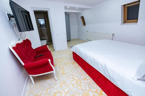 a bedroom with a bed and a red chair at Pensiunea Ewo in Iaşi