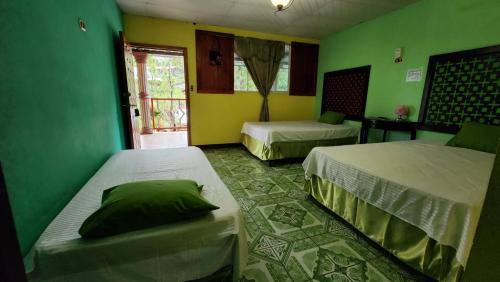 due letti in una stanza con pareti verdi di Hotel y Restaurante Las Margaritas a Perquín