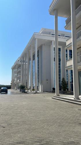 un gran edificio blanco con columnas en un estacionamiento en Marsela, en Shkodër