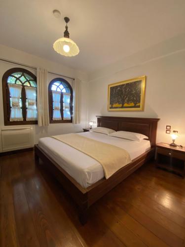 a bedroom with a large bed and two windows at Boutique Hotel Muzaka (Historic Center) in Berat