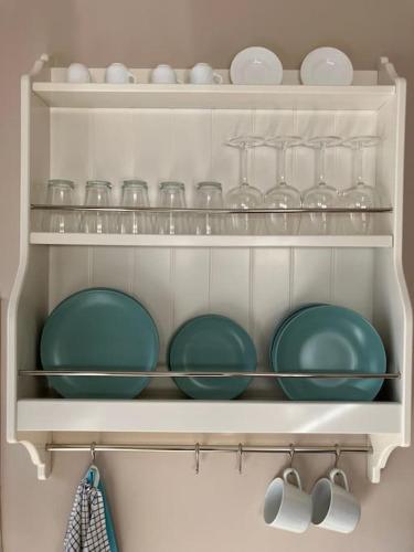 a white shelf with plates and glasses on it at A Casa da Fonte in Santa Eulalia de Oscos