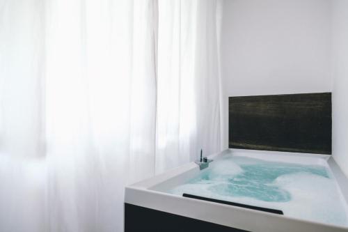 uma casa de banho branca com uma banheira e uma janela em Eveline 2 - Piscina Privata o Jacuzzi em Sanremo