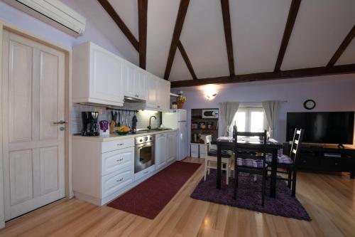 a kitchen with white cabinets and a table and a dining room at Apartment Vanja in Opatija