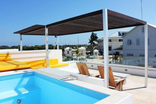 a swimming pool with a pavilion on the roof of a house at Casa Moderna Fresca and The PoolClub at Mahogany Bay! in San Pedro