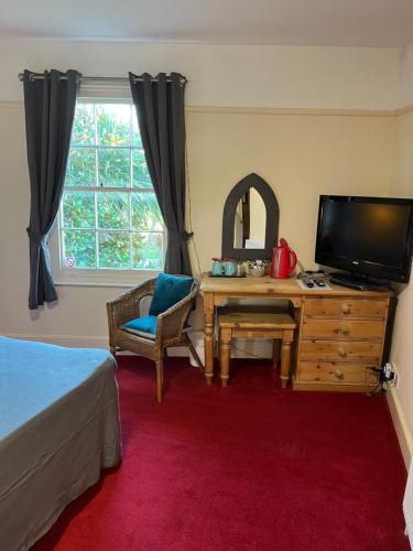 a bedroom with a bed and a tv and a desk at Castle Inn in Hythe