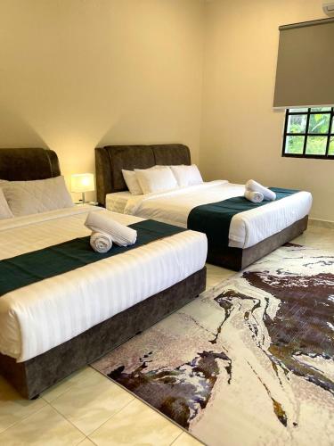 two beds in a hotel room with two bedsskirts at Villa Ruby - with private swimming pool in Kota Bharu