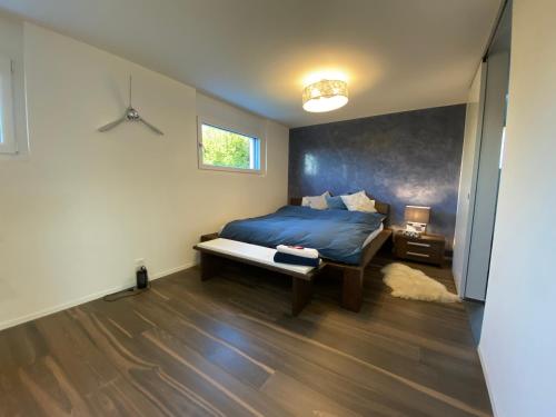 a bedroom with a bed with a blue comforter at Luxusloft mit warmem Outdoor Whirlpool in Mühleberg