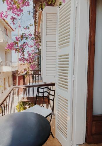a room with a table and a balcony with pink flowers at Five Seasons in Nafplio