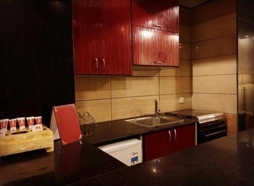 a kitchen with red cabinets and a sink at فندق بردى in Qaryat al Bulush