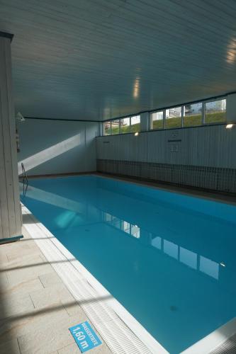 a large swimming pool with blue water in a building at Sweet Dreams Wellness Appartement in Seefeld in Tirol