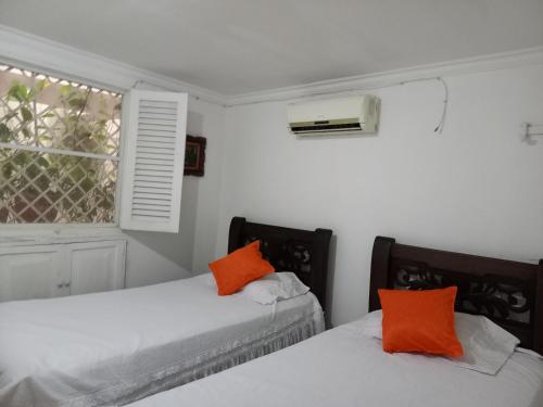 two beds in a white room with orange pillows at Apartamento centro historico in Cartagena de Indias