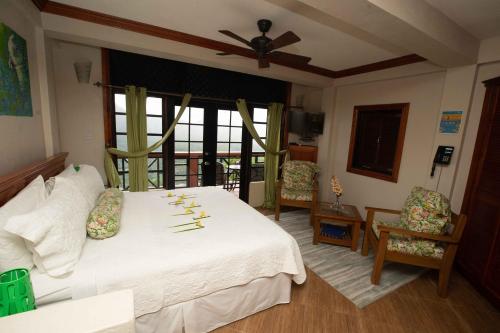 a bedroom with a white bed with a ceiling fan at Samfi Gardens in Soufrière
