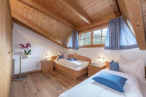 a bedroom with two beds and two windows at Bergblick App Lärche in Funes