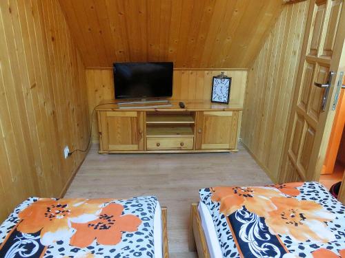 Zimmer mit 2 Betten und einem TV auf einem Schrank in der Unterkunft Domki ogrzewane Sokół in Władysławowo