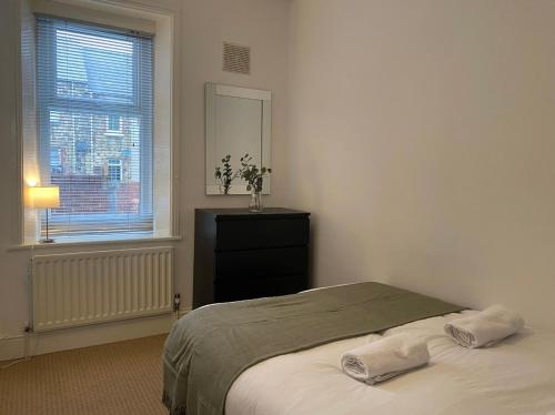 a bedroom with a bed and a dresser and a window at Alexander Apartments Gateshead North in Gateshead