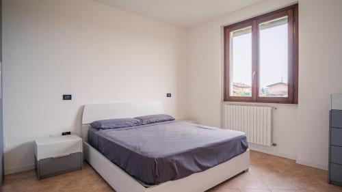 Habitación blanca con cama y ventana en The House in the Vineyard - Italian Homing, en Manerba del Garda