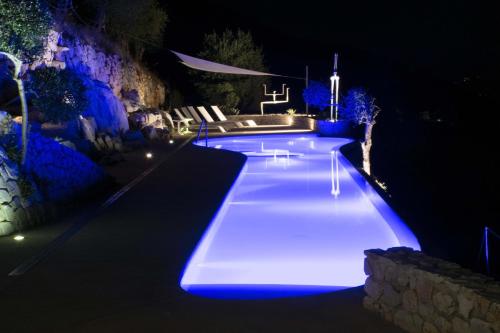una piscina iluminada por la noche con luces azules en VILLA FARFALLA & GUESTHOUSE - The world unique property with an openable roof en Lucca