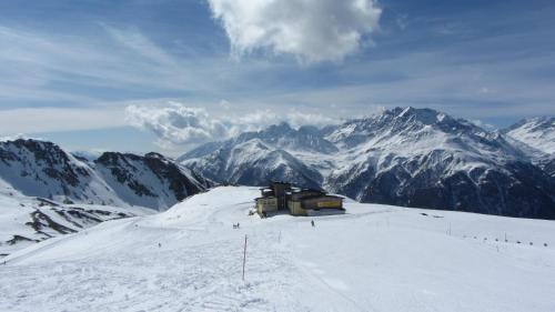 a cabin on a snow covered mountain with mountains in the background at Appartement Seppenbauer - Seppenbauerhof in Heiligenblut