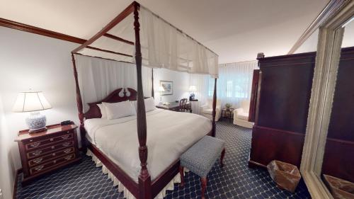 sypialnia z łóżkiem z baldachimem i komodą w obiekcie Avon Old Farms Hotel w mieście Avon