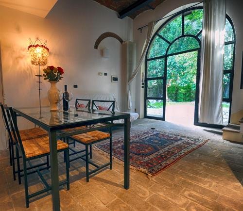 una sala da pranzo con tavolo, sedie e una grande finestra di Scuderie Il Magnifico a Firenze