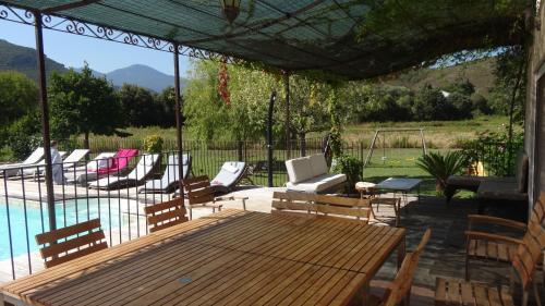 a patio with a wooden table and chairs next to a pool at Villa U Puntale in Ghisonaccia