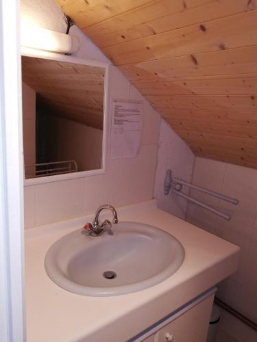 une salle de bain avec un lavabo blanc et un miroir dans l'établissement Grand gite 14 personnes ,cour ,salle de jeux, proche du village , commerces, à Murat