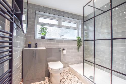 uma casa de banho com um WC, um chuveiro e uma janela. em Modernistic 4-bedroom home close to City Centre em Cardiff