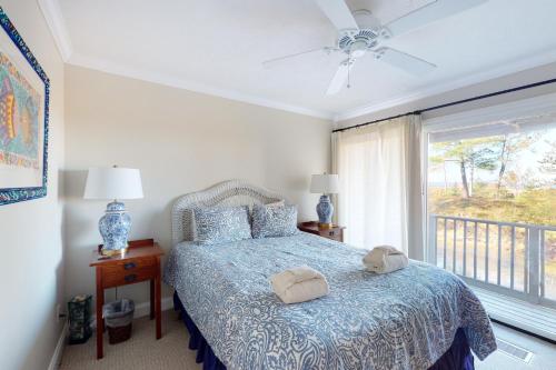 a bedroom with a bed with a blue comforter and a window at Gentle Winds 21 22 in Glen Arbor