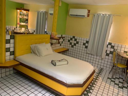 a bedroom with a bed with a yellow headboard at Motel Estoril (Adult Only) in Recife