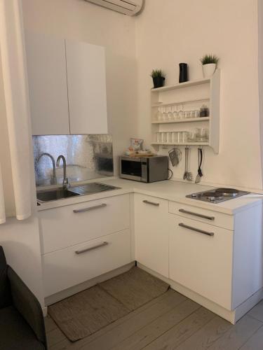 eine weiße Küche mit einer Spüle und einer Mikrowelle in der Unterkunft Mc - Piazza Mancini in Rom