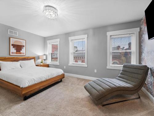 a bedroom with a bed and a chair and windows at Stylish 4 Bedroom Loft Home, North Shore, City Skyline View Close to NHL, NFL in Pittsburgh