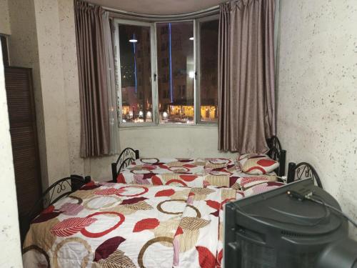 a bedroom with a bed with a flowered blanket and a window at Mamaya Hotel in Amman