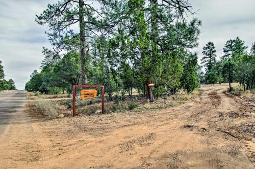 a dirt road with a sign next to trees at Fire Pit, Fenced Yard Overgaard Cabin Near Hiking in Overgaard