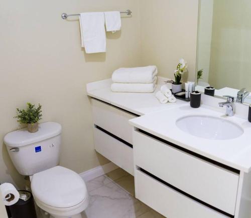 Baño blanco con aseo y lavamanos en Suite Retreat at The Lofts, en Kingston
