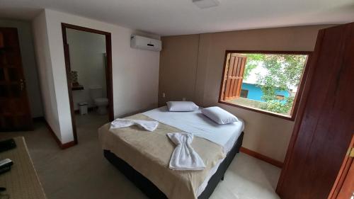 a bedroom with a bed with a towel on it at Pousada Cordel de Itaúnas in Itaúnas