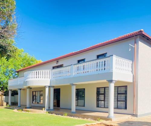a large white building with a balcony on top at Airport Royal Guest House in Kempton Park