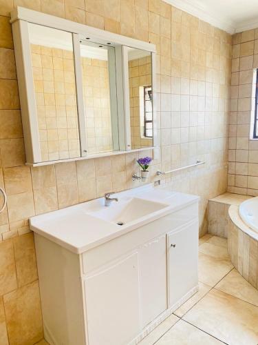 a bathroom with a sink and a mirror and a tub at Airport Royal Guest House in Kempton Park