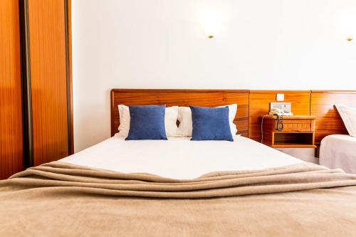 a bedroom with a large bed with blue pillows at Dona Amélia Hotel by RIDAN Hotels in Fátima