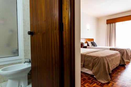 uma casa de banho com uma cama e um lavatório num quarto em Dona Amélia Hotel by RIDAN Hotels em Fátima